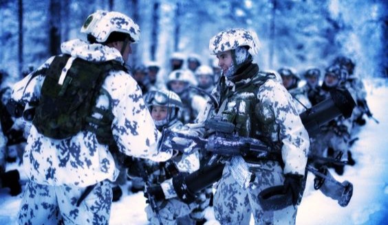 Maavoimien komentaja kenraaliluutnantti Pasi Välimäki kättelee varusmiestä, molemmilla on päällään talvivarustus.