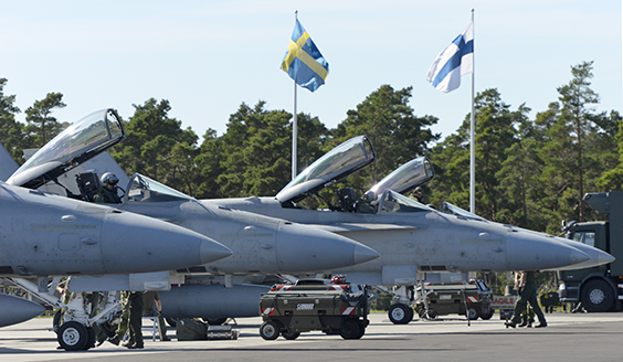 Finnish F/A-18 Hornet fighter jets with the flags of Finland and Sweden in the background