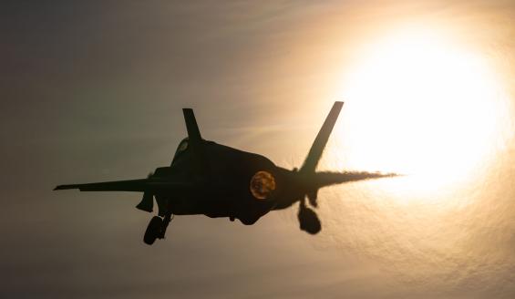 Yhdysvaltalainen F-35-hävittäjä lähdössä lentoon. Koneesta näkyy vaaleaa taivasta vasten lähinnä tumma siluetti ja jälkipolttimen hehku. Ilma väreilee kirkaan auringon edessä.