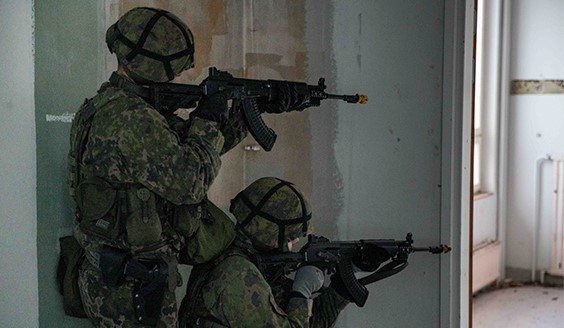 Kaksi sotilaspoliisia harjoittelee etsintää ja kiinniottoa rakennuksen sisällä.