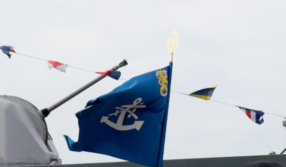 Rannikkolaivaston lippu hulmuaa laivatykin putken edessä.